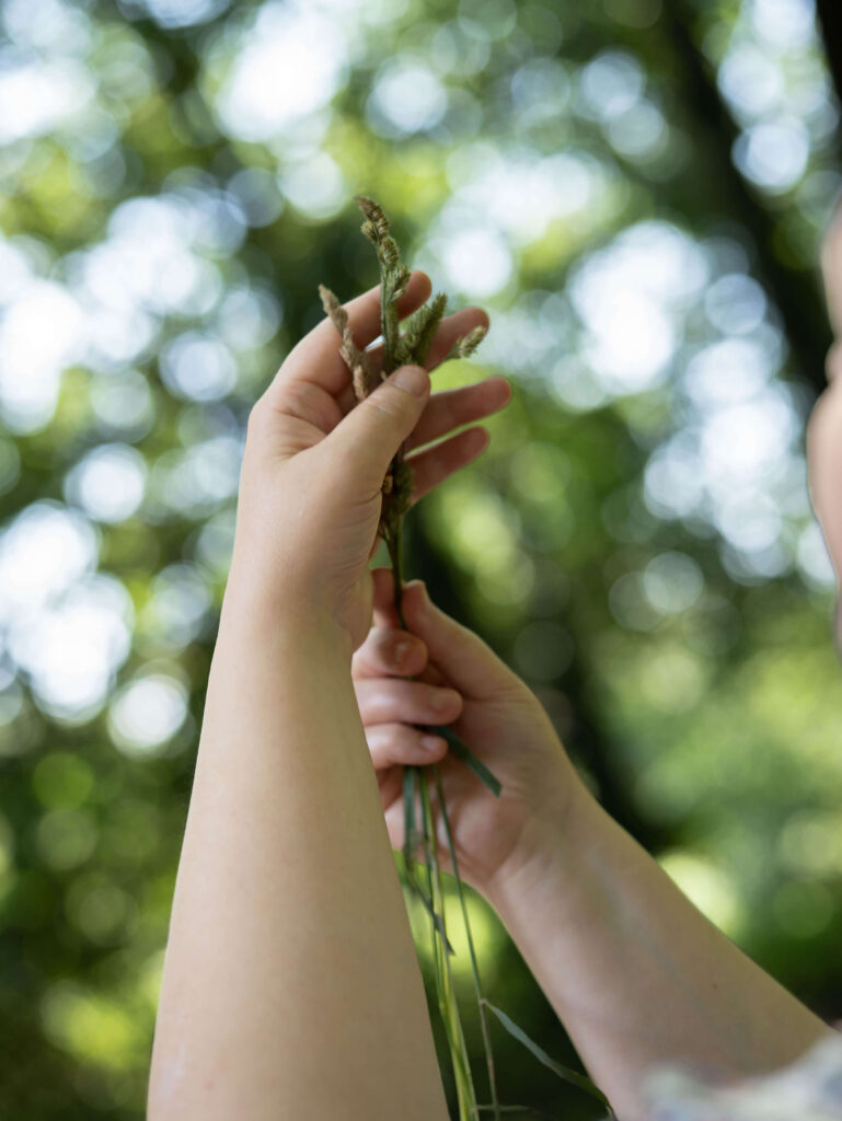 Adina's hands holding grass in the air